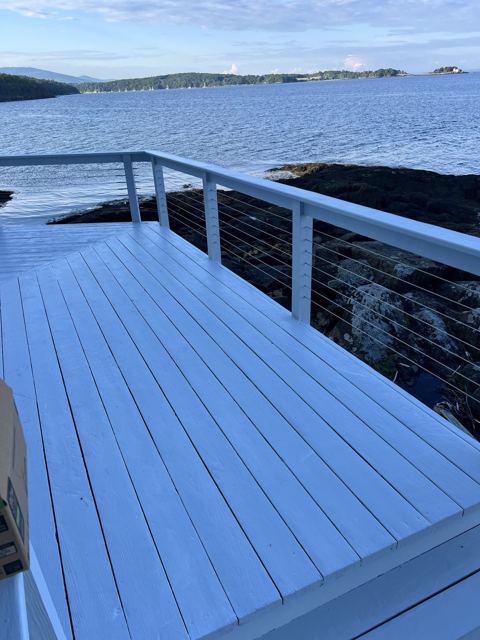 Freshly painted deck boards beside a cable railing