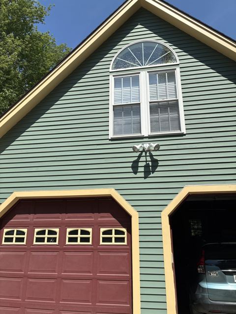 Green clapboard house repainted with yellow trim and burgundy garage doors